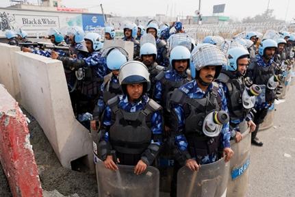 Police officers stand guards as barricades are erected on a national highway to stop farmers