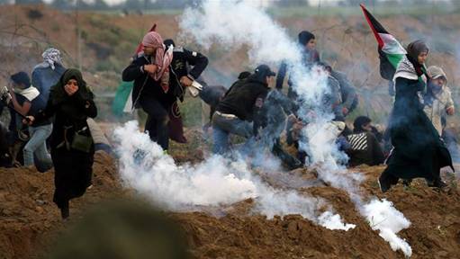 Palestinian demonstrators run away from teas gas fired by Israeli forces during a protest at the Israeli fence in the southern Gaza Strip [File: Ibraheem Abu Mustafa/Reuters]